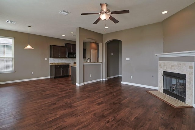 unfurnished living room with dark hardwood / wood-style flooring, a tile fireplace, and ceiling fan