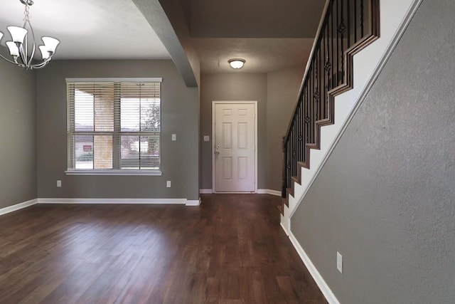 foyer featuring dark wood-type flooring and a chandelier