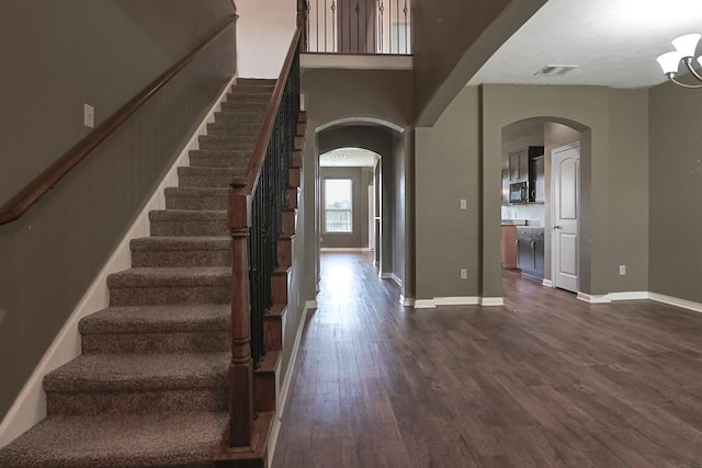 foyer entrance with dark wood-type flooring and a towering ceiling