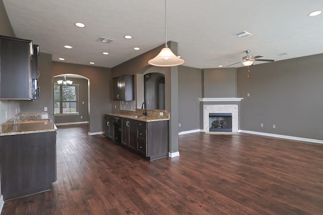 kitchen featuring sink, a tile fireplace, dark hardwood / wood-style floors, dark brown cabinetry, and decorative light fixtures