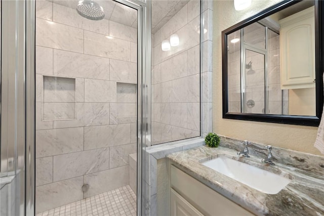 bathroom with a textured wall, a shower stall, and vanity