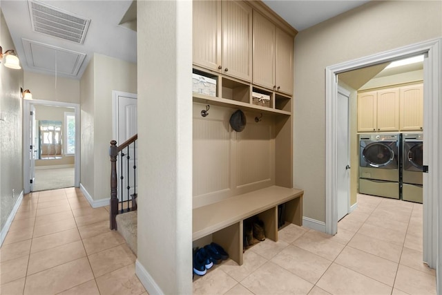 mudroom with light tile patterned flooring, visible vents, baseboards, washer and dryer, and attic access