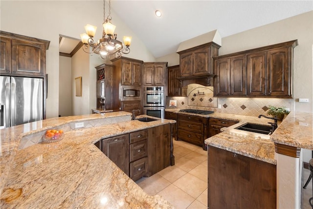 kitchen featuring light stone counters, dark brown cabinetry, a sink, hanging light fixtures, and appliances with stainless steel finishes