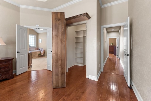 corridor featuring crown molding, baseboards, and wood finished floors