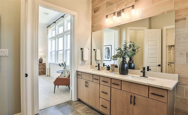 ensuite bathroom with ensuite bathroom, double vanity, a sink, and tile patterned floors