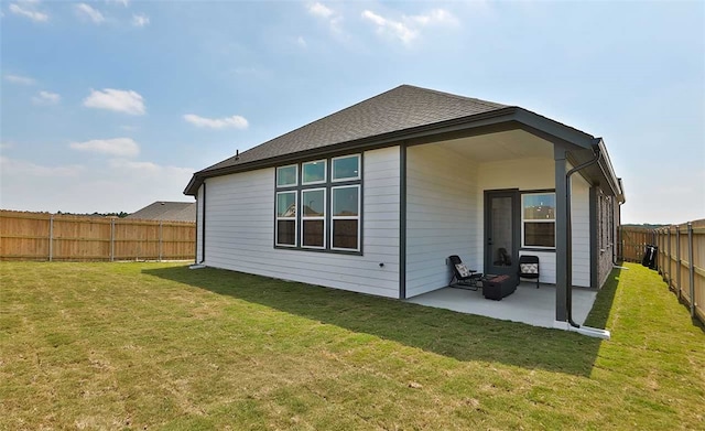 back of property with a yard, a shingled roof, a patio, and a fenced backyard