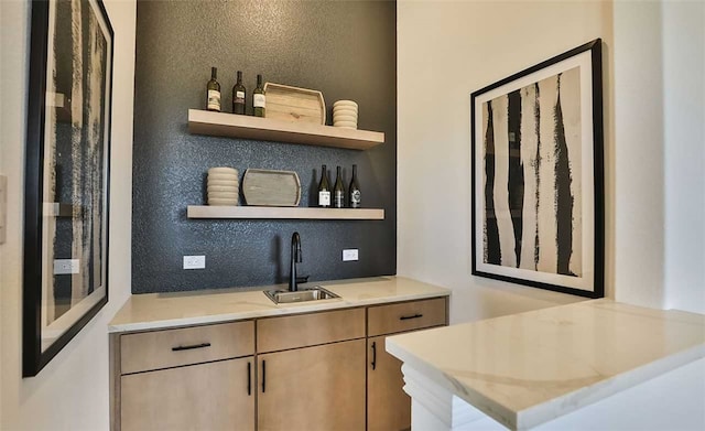 bar with a textured wall, indoor wet bar, and a sink