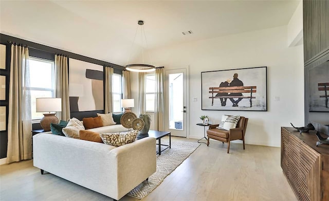 living area with baseboards, light wood-style flooring, visible vents, and a wealth of natural light