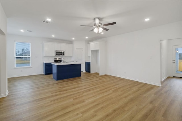 kitchen featuring white cabinetry, an island with sink, appliances with stainless steel finishes, and light hardwood / wood-style flooring