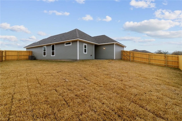 back of property with central AC unit and a lawn