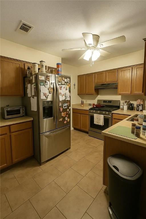 2106 Labrisa Dr, Bryan, TX 77807 - kitchen with stainless steel appliances, under cabinet range hood, ceiling fan, light tile patterned flooring, and light countertops
