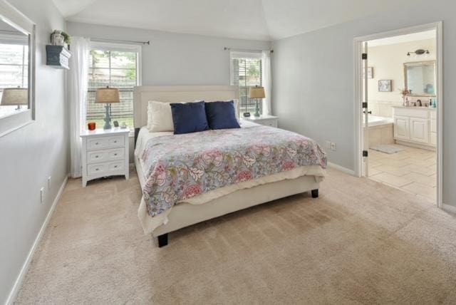 bedroom with ensuite bath, baseboards, vaulted ceiling, and light colored carpet