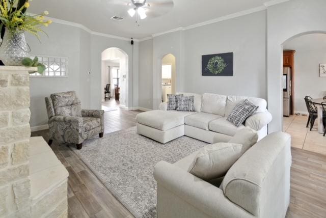 living room with visible vents, arched walkways, wood finished floors, and ornamental molding