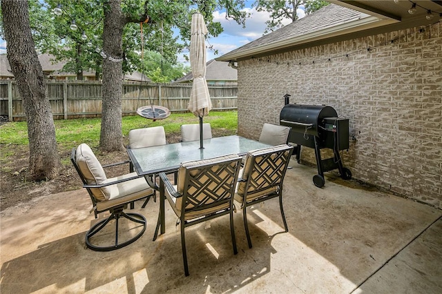 view of patio with outdoor dining area, area for grilling, and fence