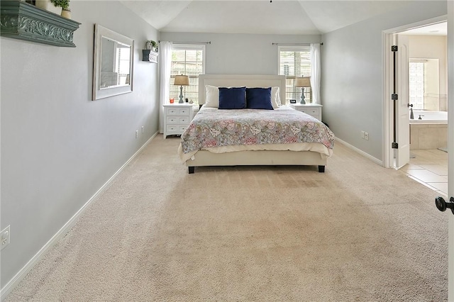 bedroom with ensuite bathroom, baseboards, vaulted ceiling, and light colored carpet