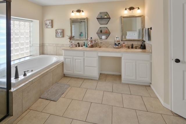 bathroom with double vanity, a garden tub, tile patterned flooring, and a sink