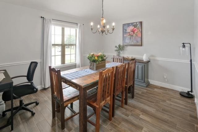 dining room with a notable chandelier, baseboards, and wood finished floors