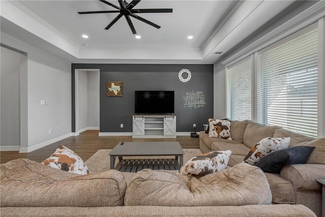 living room with ornamental molding, dark hardwood / wood-style floors, ceiling fan, and a tray ceiling