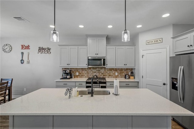 kitchen featuring decorative light fixtures, dark hardwood / wood-style floors, an island with sink, and appliances with stainless steel finishes