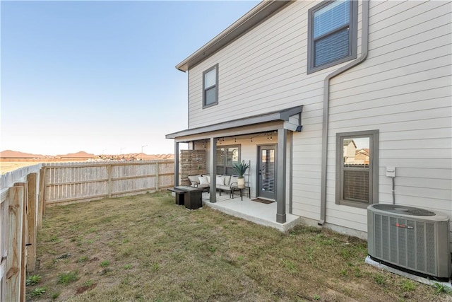 back of house featuring central AC unit, an outdoor living space, a fenced backyard, a patio area, and a lawn