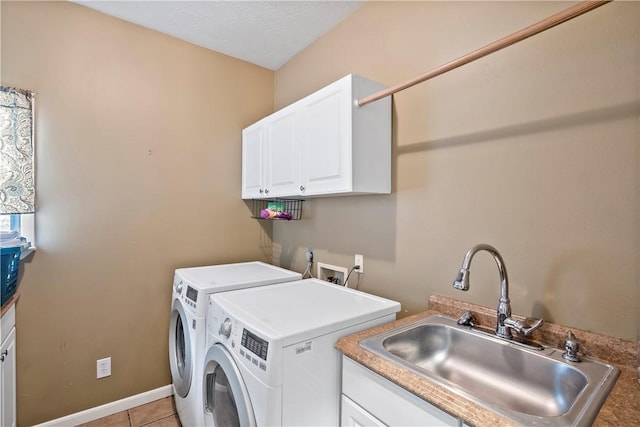 laundry area with light tile patterned floors, baseboards, washer and dryer, a sink, and cabinet space