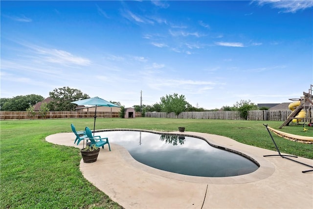 view of swimming pool with a patio area, a storage unit, an outbuilding, a fenced backyard, and a lawn