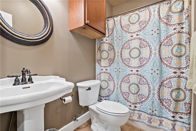 bathroom featuring toilet, baseboards, a sink, and curtained shower
