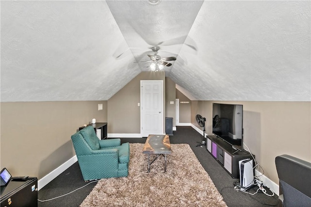 living room with lofted ceiling, a textured ceiling, carpet floors, a ceiling fan, and baseboards