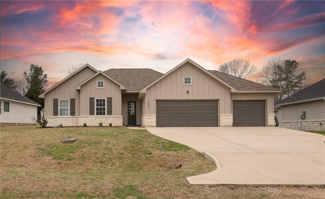 view of front of property with an attached garage, driveway, stone siding, a lawn, and board and batten siding