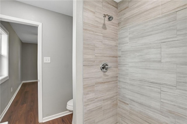 bathroom featuring hardwood / wood-style flooring, tiled shower, and toilet