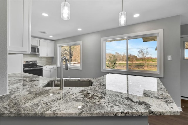 kitchen featuring white cabinetry, appliances with stainless steel finishes, sink, and decorative light fixtures