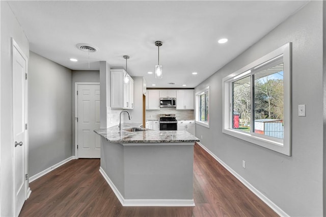 kitchen with appliances with stainless steel finishes, sink, hanging light fixtures, and white cabinets