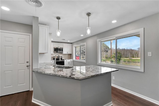 kitchen with sink, appliances with stainless steel finishes, white cabinetry, light stone counters, and decorative light fixtures