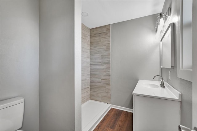 bathroom featuring vanity, a shower, hardwood / wood-style floors, and toilet