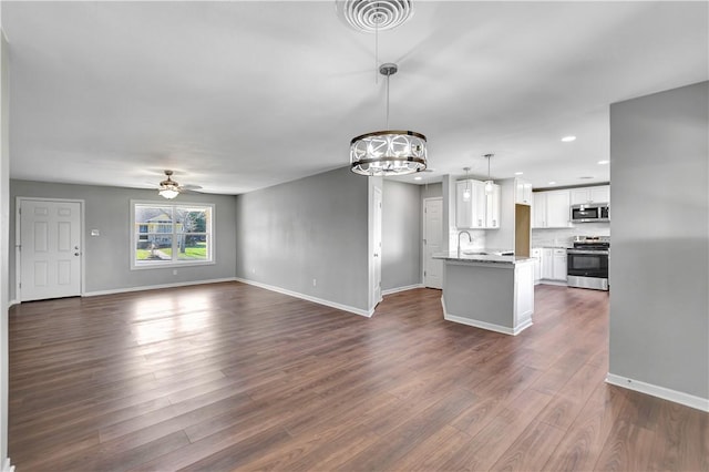 kitchen featuring hanging light fixtures, stainless steel appliances, white cabinets, dark hardwood / wood-style flooring, and ceiling fan with notable chandelier