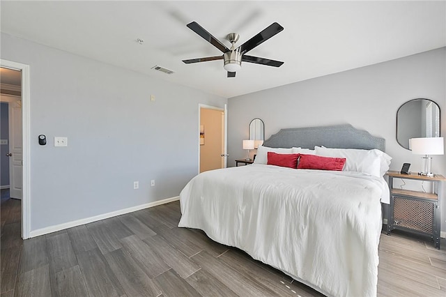 bedroom featuring ceiling fan, wood finished floors, visible vents, and baseboards