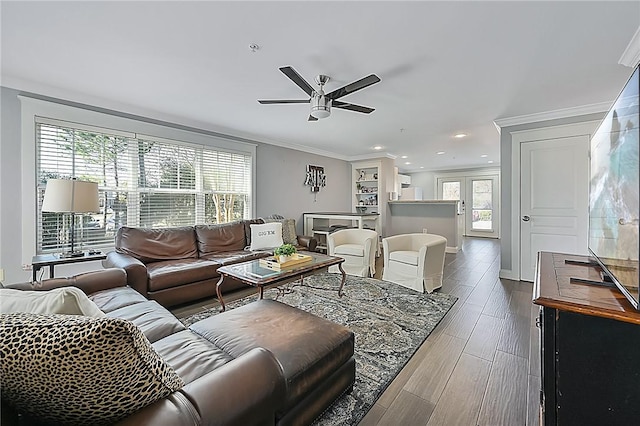 living area with ornamental molding, a healthy amount of sunlight, baseboards, and wood finished floors