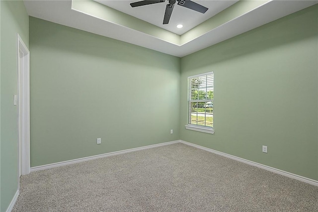 carpeted empty room featuring a raised ceiling and ceiling fan