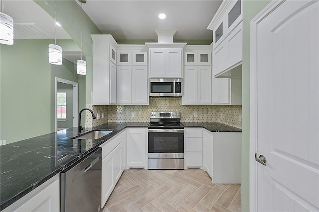 kitchen featuring sink, dark stone countertops, decorative light fixtures, white cabinetry, and stainless steel appliances