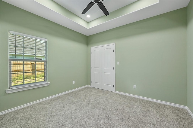 spare room with carpet floors, a raised ceiling, plenty of natural light, and ceiling fan