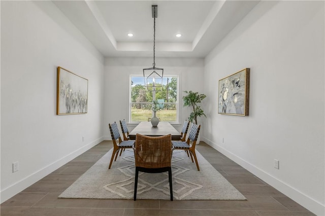 dining room with a tray ceiling and dark wood-type flooring