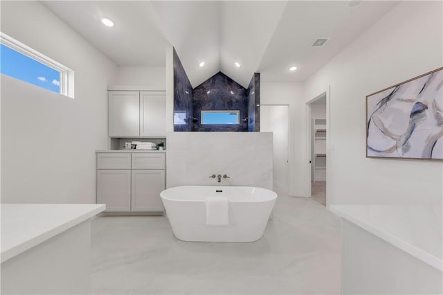 bathroom featuring vanity, lofted ceiling, a tub, and concrete floors
