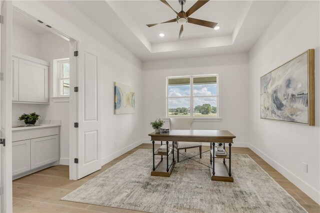 office space featuring light hardwood / wood-style flooring, a raised ceiling, and ceiling fan