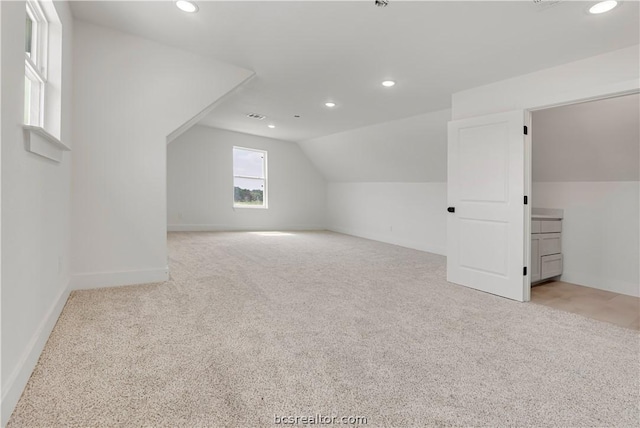 additional living space with light colored carpet and vaulted ceiling