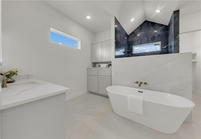 bathroom featuring vanity, vaulted ceiling, tile walls, a tub to relax in, and concrete floors