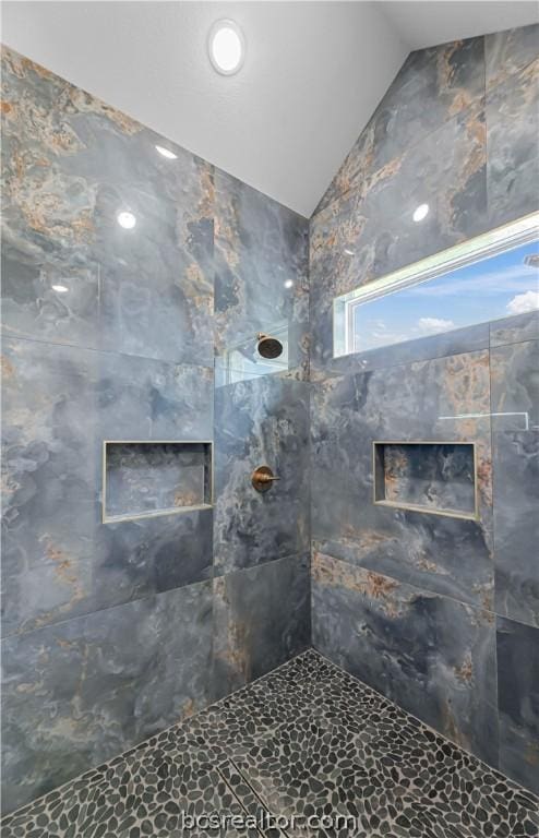 bathroom featuring lofted ceiling and tiled shower