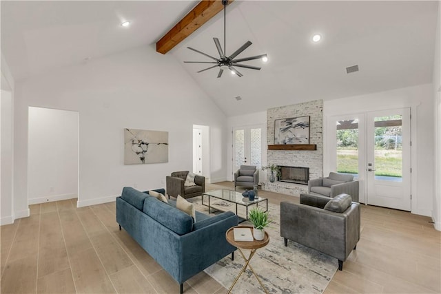 living room featuring ceiling fan, high vaulted ceiling, beamed ceiling, a fireplace, and light hardwood / wood-style floors