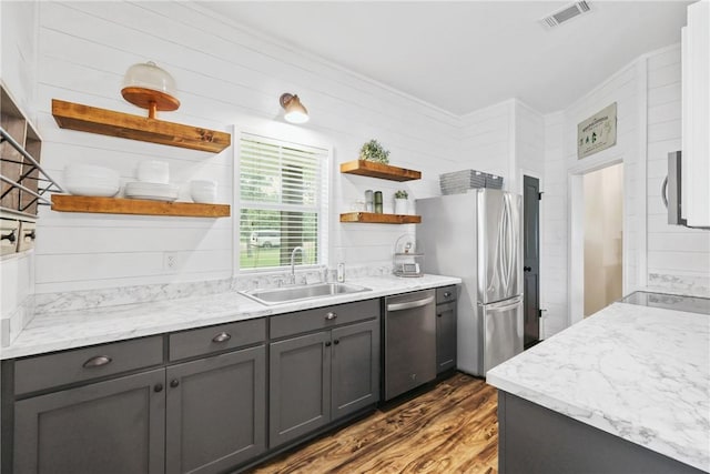 6866 Wooded Dr, College Station, TX 77845 - kitchen with open shelves, appliances with stainless steel finishes, wood finished floors, gray cabinetry, and light stone countertops