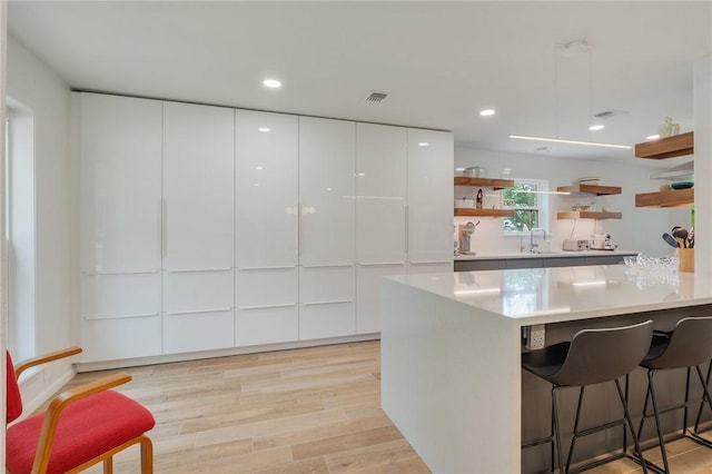 1003 Guadalupe Dr, College Station, TX 77840 - kitchen with modern cabinets, open shelves, a breakfast bar area, white cabinets, and light countertops