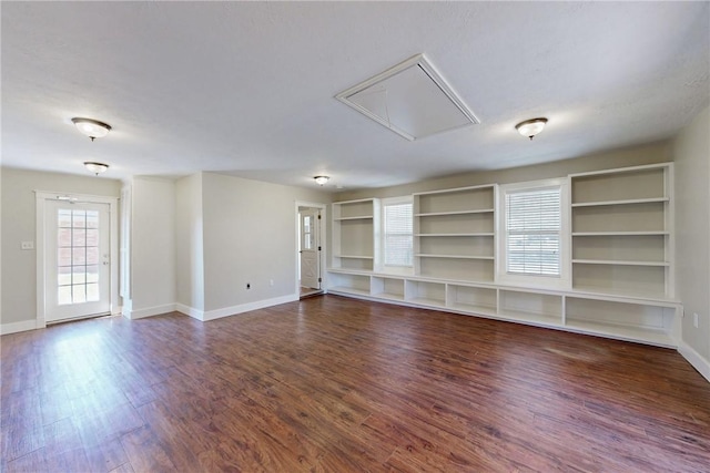 empty room with wood finished floors, attic access, and baseboards